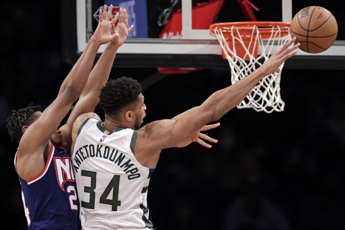 Milwaukee Bucks forward Giannis Antetokounmpo (34) passes the ball in front of Brooklyn Nets guard Cam Thomas during the first half of an NBA basketball game Friday, Jan. 7, 2022, in New York. (AP Photo/Adam Hunger)