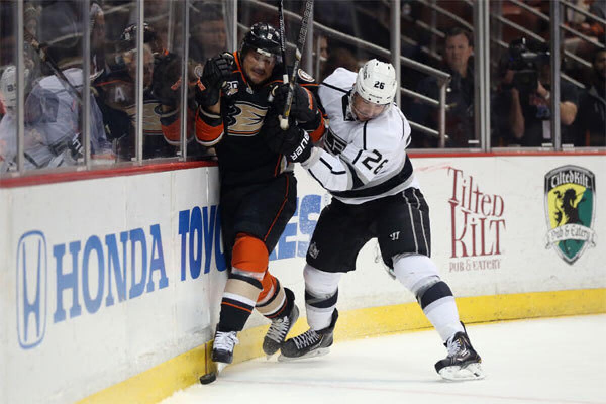 Teemu Selanne of the Ducks is checked into the boards by Slava Voynov of the Kings on Jan. 23.