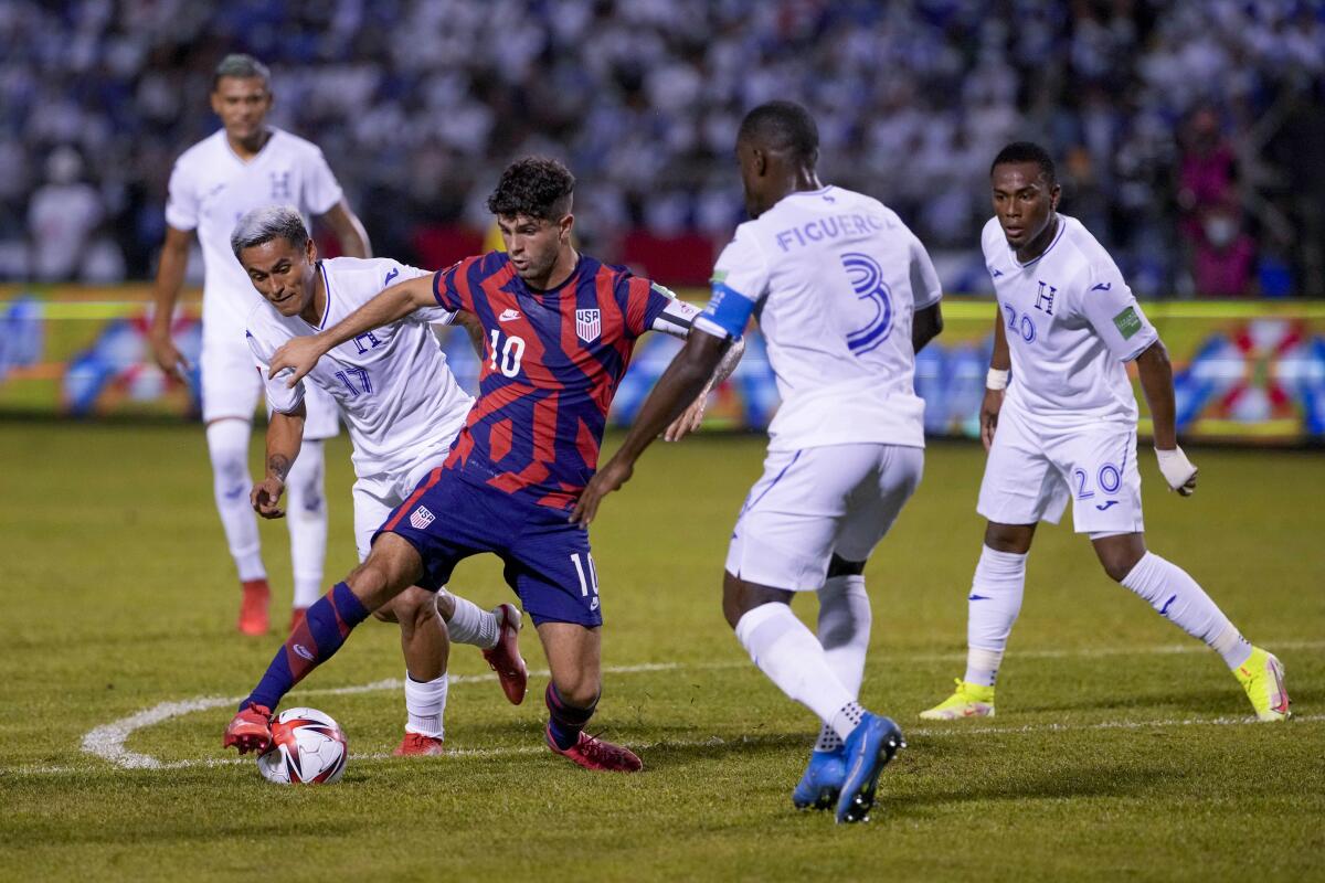 Christian Pulisic dribbles the ball surrounded by Honduras players