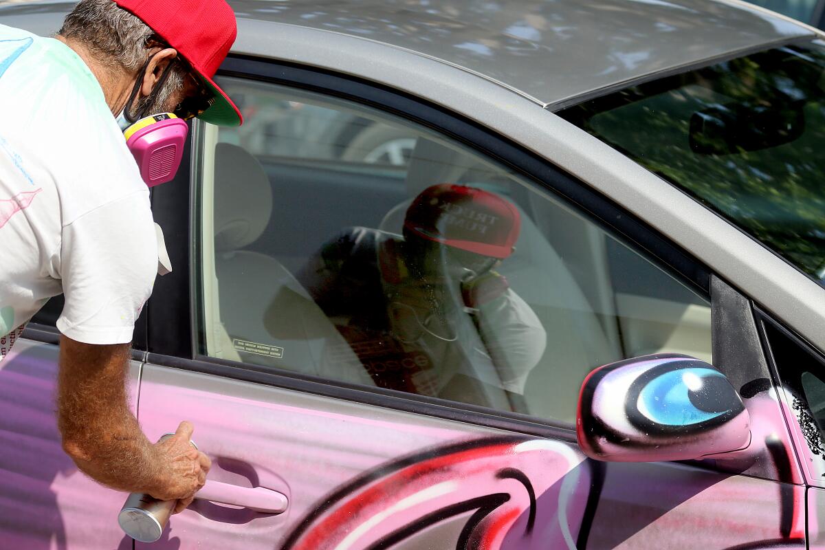Kenny Scharf paints a Prius pink at the Karbombz! rally Saturday.