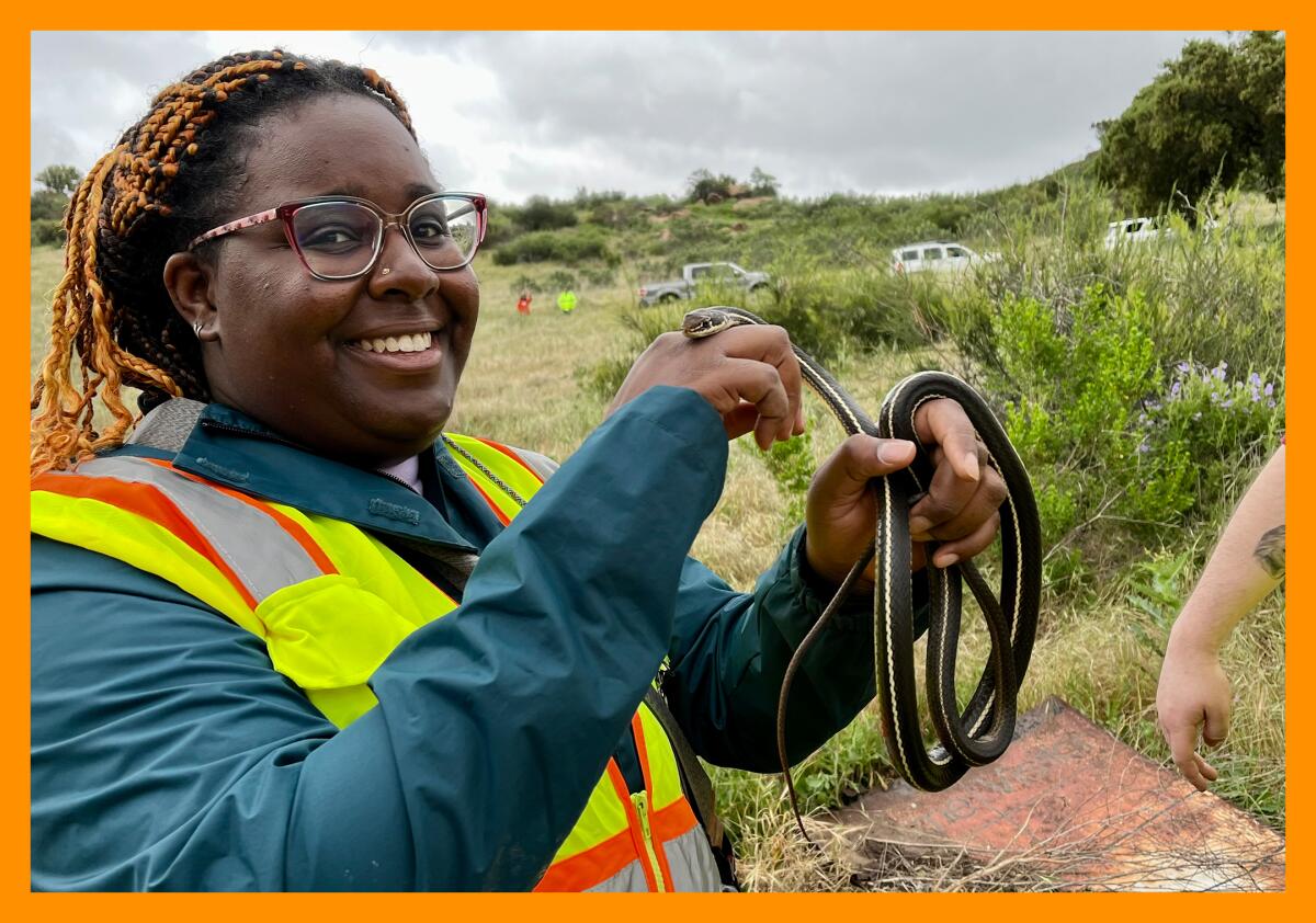 Earyn McGee smiles while holding a dark-colored snake in her hands