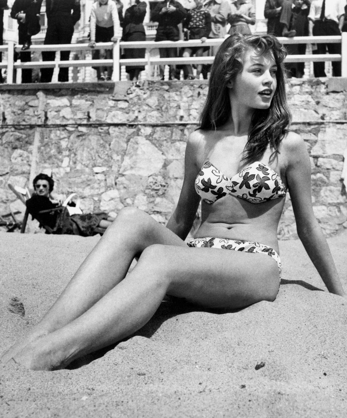 French actress Brigitte Bardot sitting on the beach during the Cannes Film Festival in 1953.