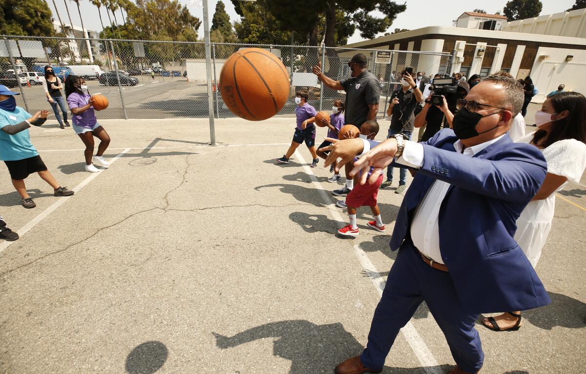 Education Secretary Miguel Cardona tosses a basketball.