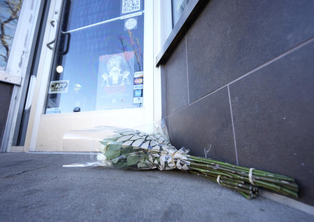 Bouquets of flowers lie on the ground outside a door