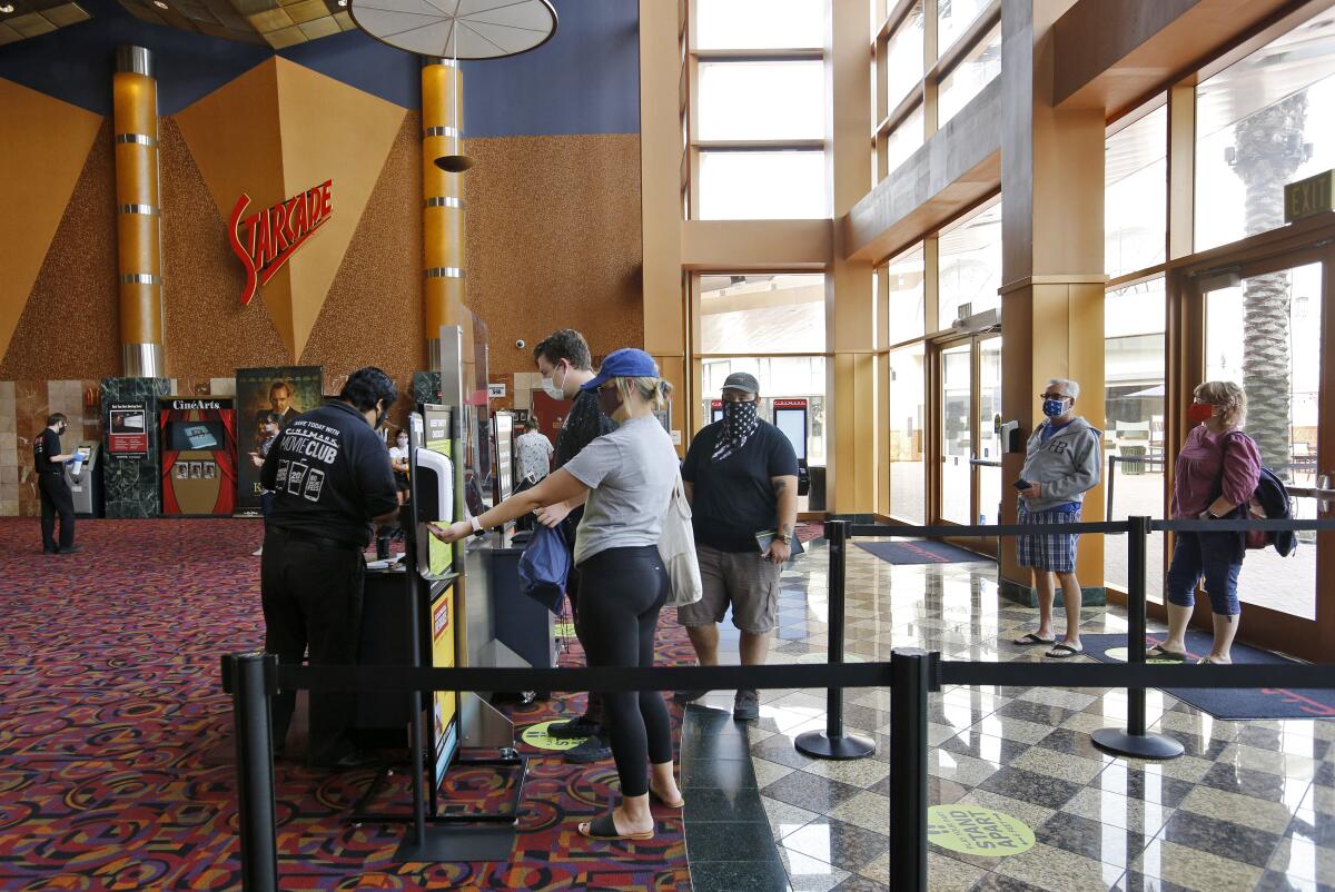 Movie fans buy their tickets minutes after Cinemark Century Cinema opened in Huntington Beach on Friday.