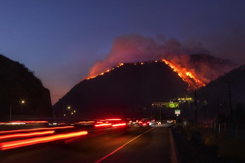 ??LOS ANGELES TIMES Traffic continues as flames roar up a steep hillside near the Getty Center in Los Angeles. The blaze forced evacuations and has burned more than 600 acres.