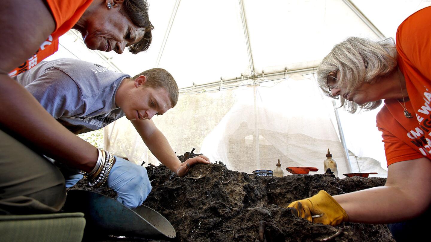 Volunteer Judith Sydner-Gordon, from left, preparator Sean Campbell and volunteer Barbara Hill work on exposing fossils at the La Brea Tar Pits.