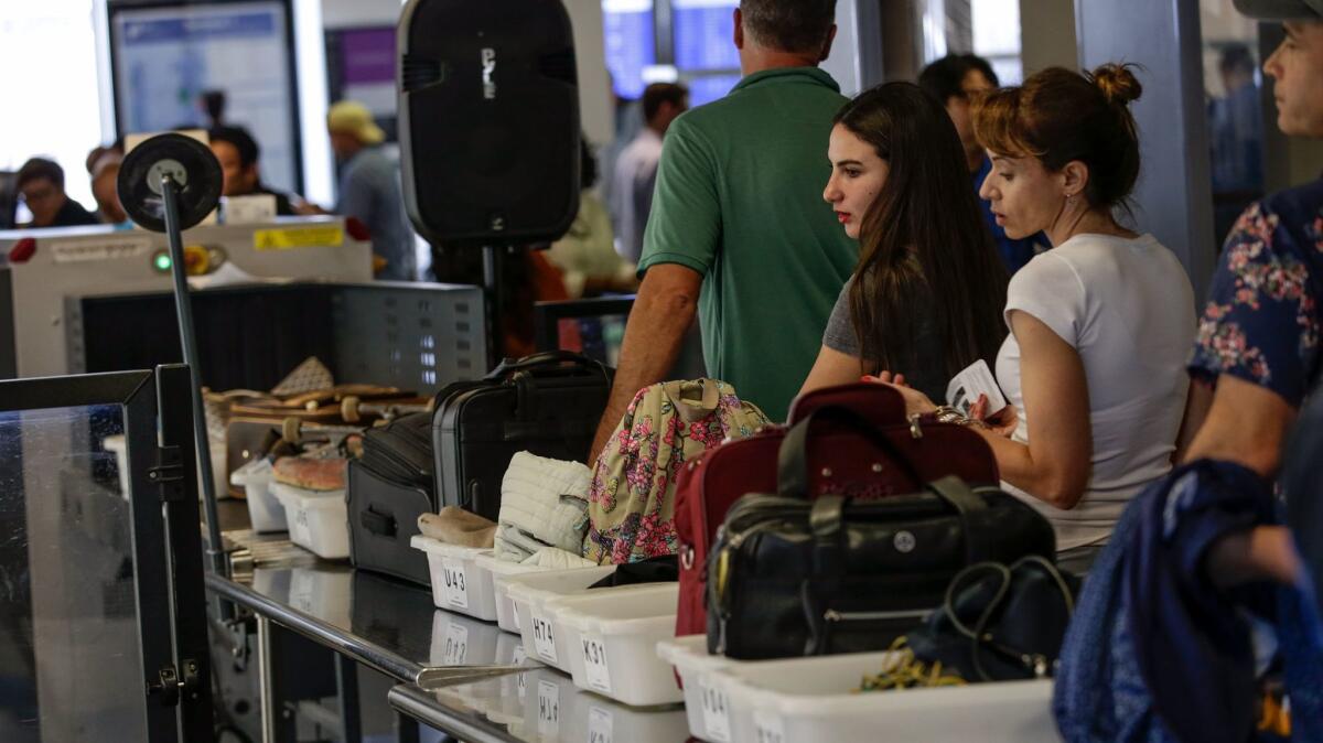 Travelers line up at a security checkpoint at Los Angeles International Airport. The Transportation Security Administration says it set a new record for screening passengers this summer: 239 million.