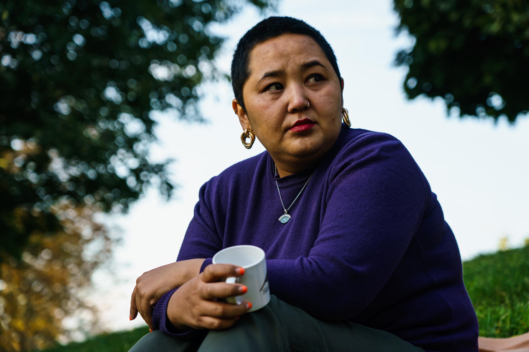 Femme tient une tasse de café dans le parc