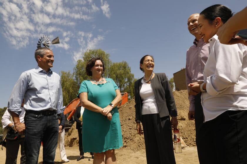Irvine, California-Aug. 18, 2022-At the Rattlesnake Recycled Water Pump Station, Secretary of the Interior Deb Haaland, third from right, speaks to the other leaders regarding the Bipartisan Infrastructure Law which allocates a total of $8.3 billion for Reclamation infrastructure projects to repair aging water delivery systems. From left is Wade Crowfoot, Secretary of Natural Resources, State of California, second from left; Congresswoman Katie Porter (CA-45), third from left, Secretary of the Interior Deb Haaland, fourth from left, Bureau of Reclamation Commissioner Camille Calimlim Touton, far right; and Paul Cook, general manager of the Irvine Ranch Water District, second from right. (Carolyn Cole / Los Angeles Times)