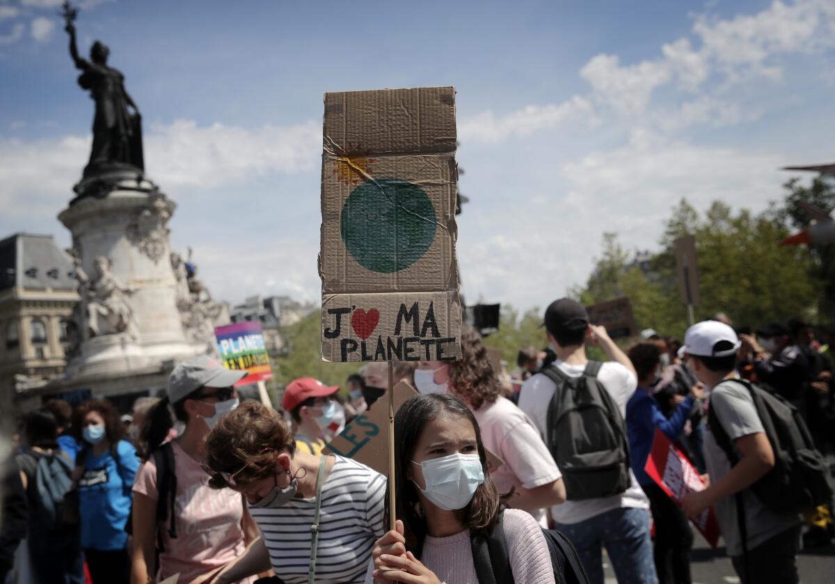 Una joven sostiene un letrero con la frase "Amo a mi planeta" en francés,