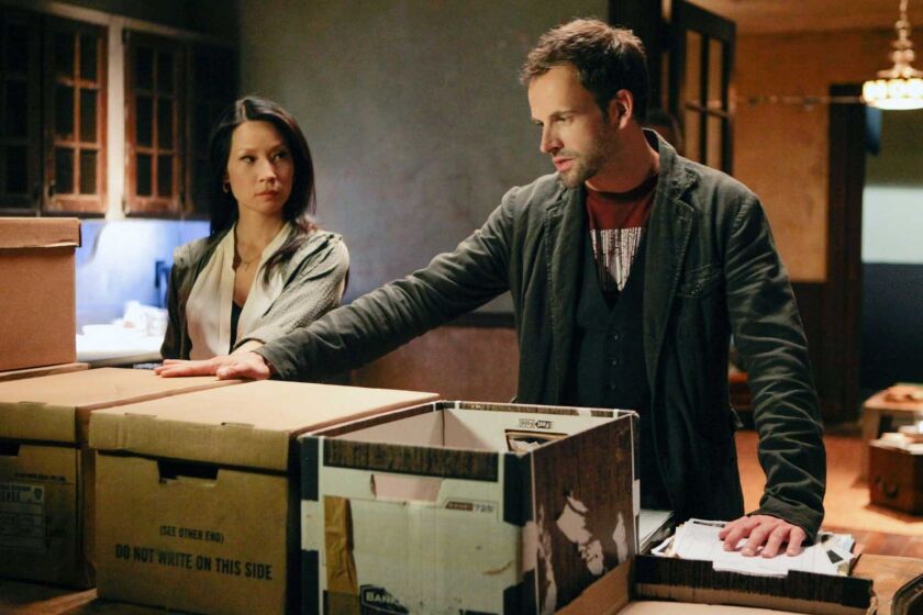 Jonny Lee Miller and Lucy Liu in a scene from CBS' "Elementary," one of at least 18 series being renewed by CBS.