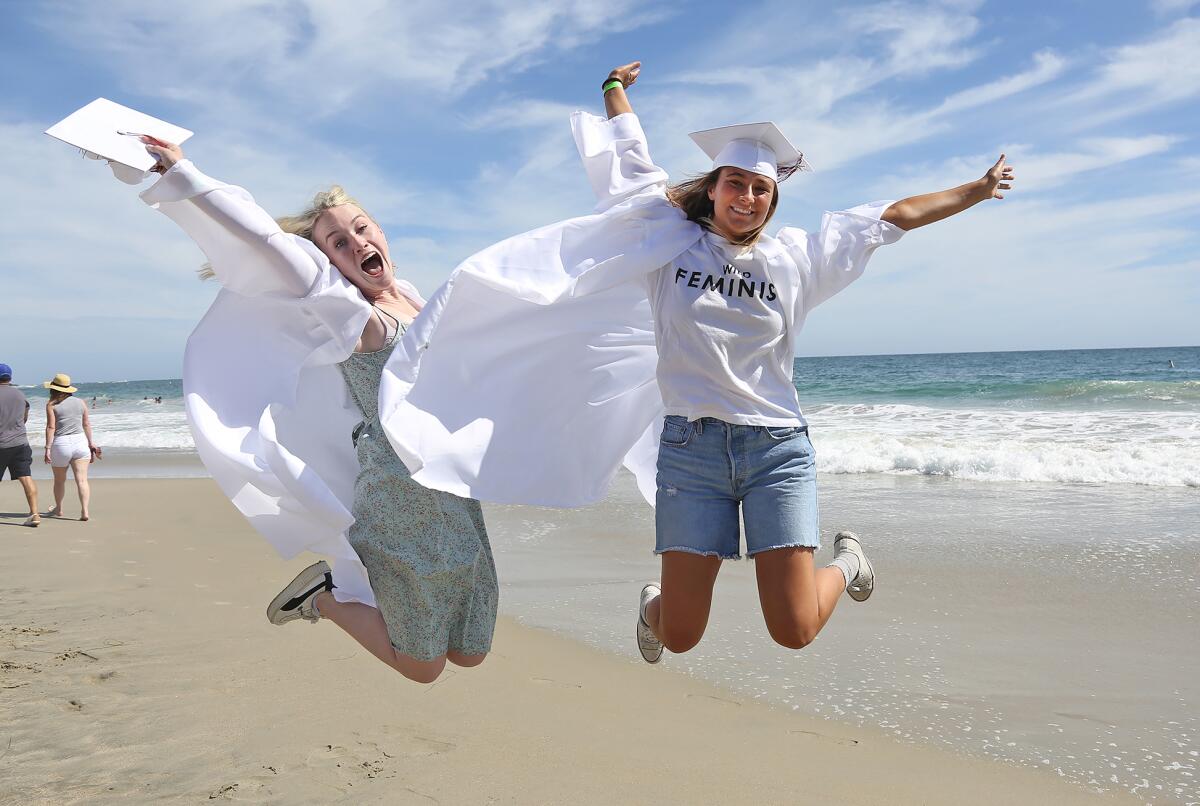 Graduates Katelyn Kolberg and Tess Booth, from left, jump for joy.