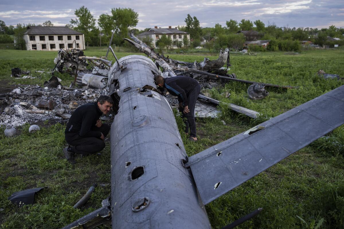Oleksiy Polyakov, derecha, y Roman Voitko revisan los restos de un helicóptero ruso 