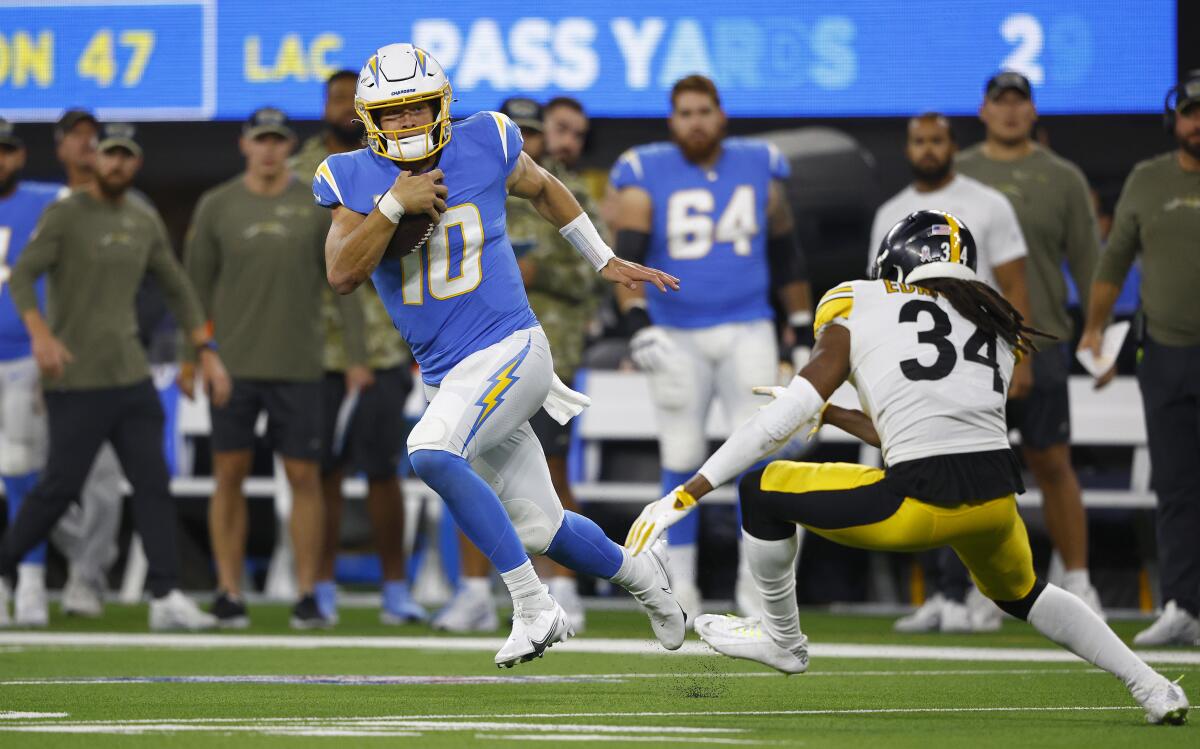 Justin Herbert of the Chargers runs past Terrell Edmunds of the Steelers for some of his 90 yards Sunday night.