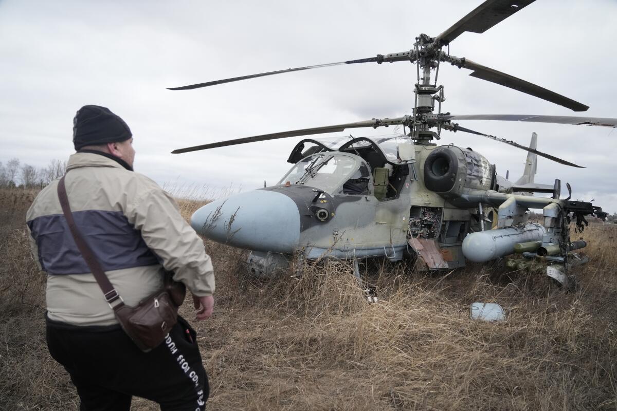 A man stands in front of a Russian helicopter gunship that was forced to land in a field outside Kyiv, Ukraine, on Feb. 24.