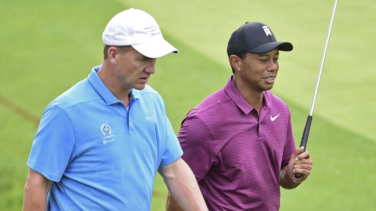 Peyton Manning, left, and Tiger Woods walk to the green on the 11th hole during the Memorial Tournament pro-am in Dublin, Ohio, on May 30.
