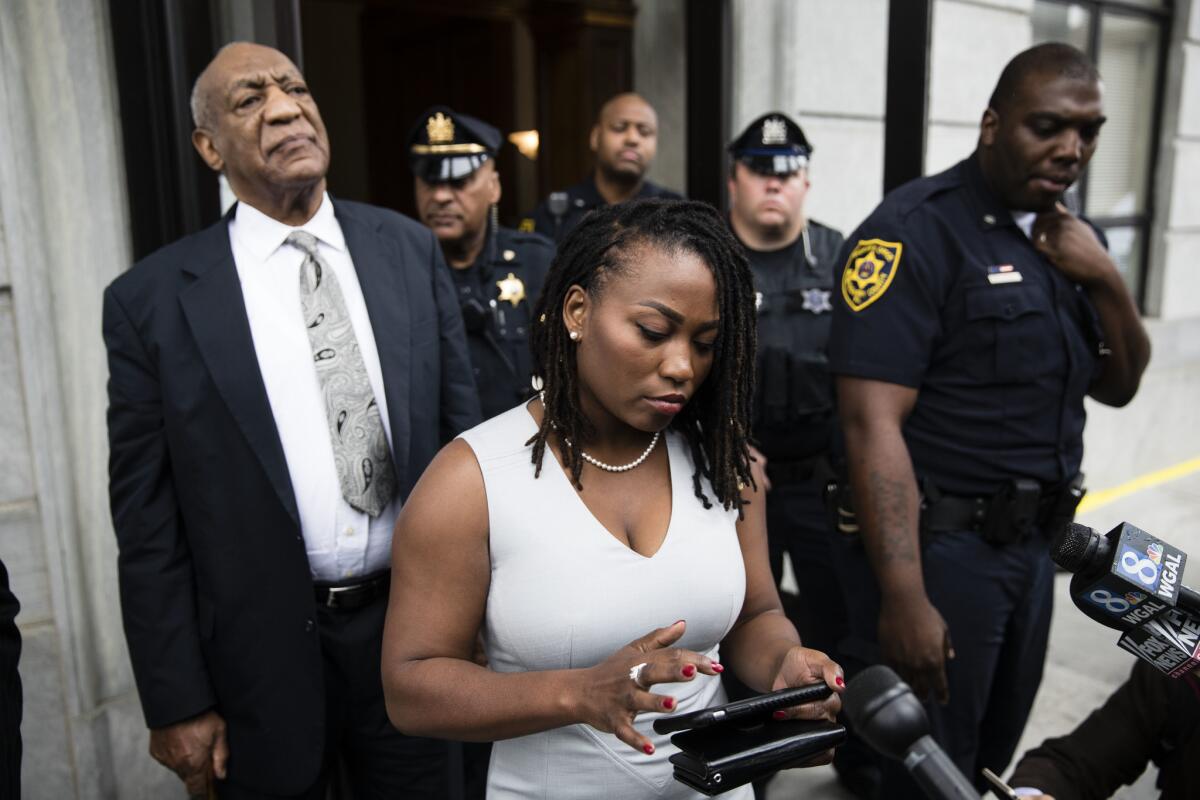 Bill Cosby listens as aide Ebonee Benson reads a statement from his wife, Camille, outside the Montgomery County courthouse after a mistrial was declared in his sexual assault case.