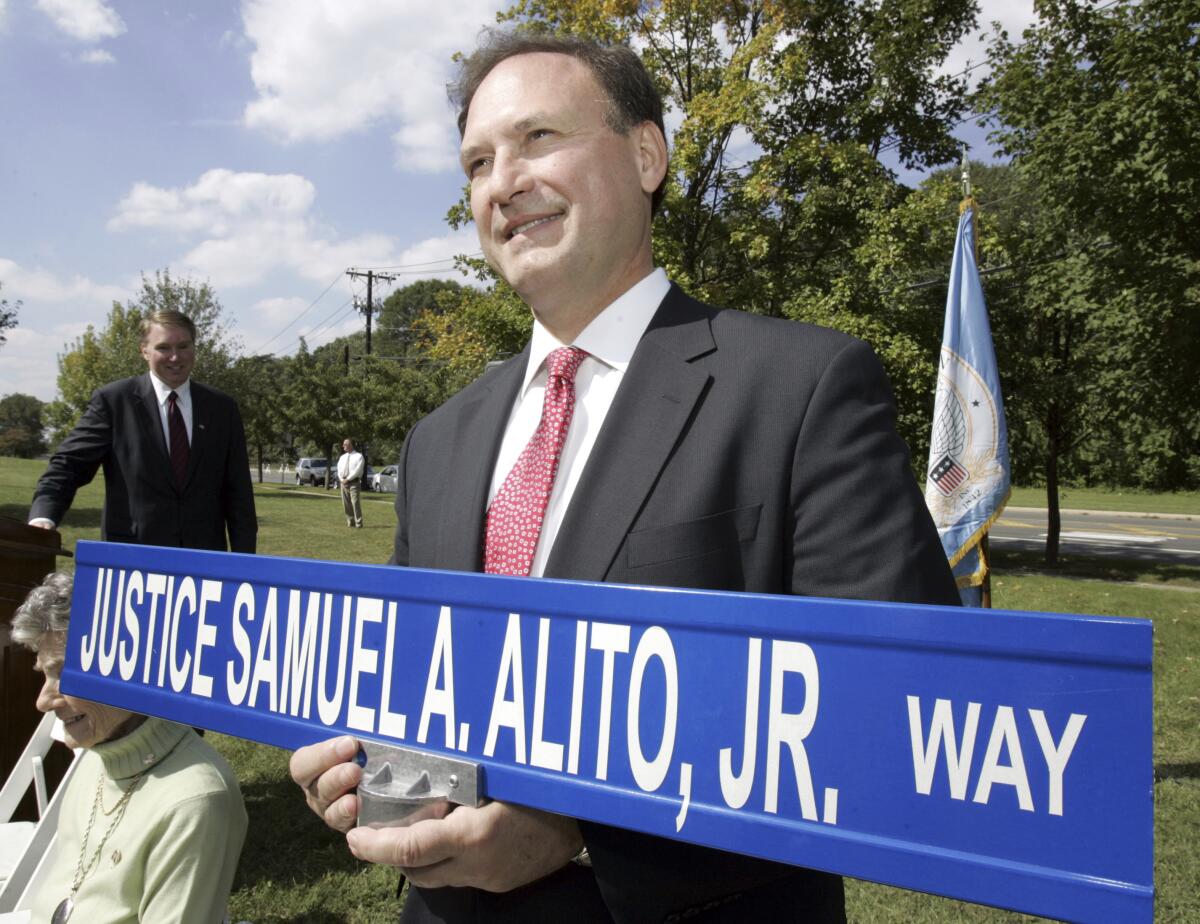 Supreme Court Justice Samuel A. Alito holds a street sign bearing his name.