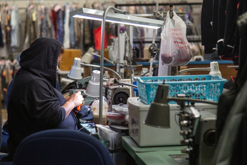 An employee at G.I. Joe's Army & Navy Surplus store in Oceanside makes apparel alterations.