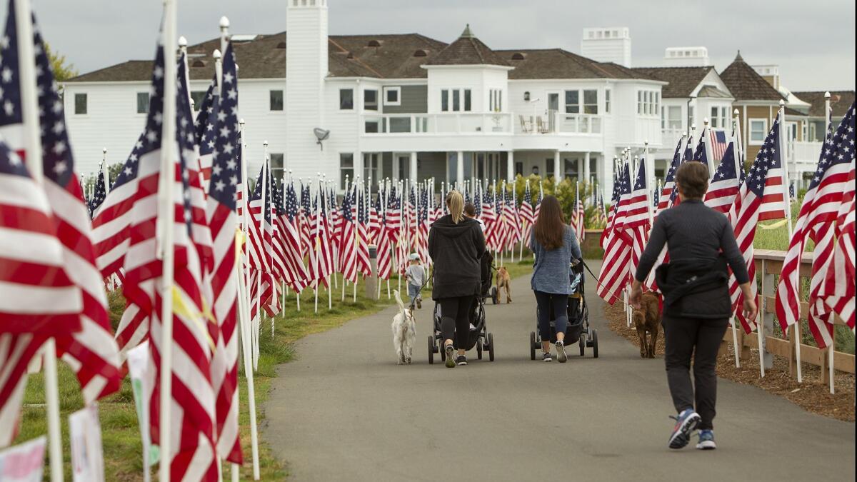 Morning walkers stroll through the Field of Honor, filled with 1,776 US flags, at Castaways Park in Newport Beach on Tuesday. The Exchange Club of Newport Harbor is hosting its 9th annual Field of Honor which will be on display through Memorial Day.