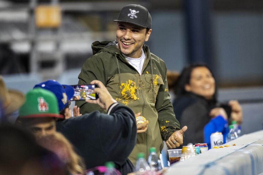 Covered in cheese, a fan holds Justin Turner's home run ball after it ball landed in his nachos.