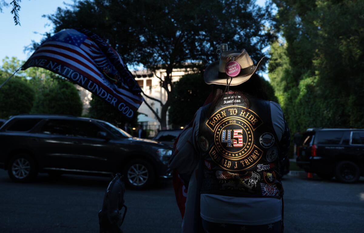 A Donald Trump supporter stands outside a home in Beverly Hills, California where the 