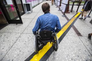 LOS ANGELES, CALIF. -- THURSDAY, SEPTEMBER 26, 2019: Television writer David Radcliff navigates his wheelchair over an electric cable channel at The Bloc shopping complex after rolling out of Metro’s 7th Street Station in Los Angeles, Calif., on Sept. 26, 2019. (Brian van der Brug / Los Angeles Times)
