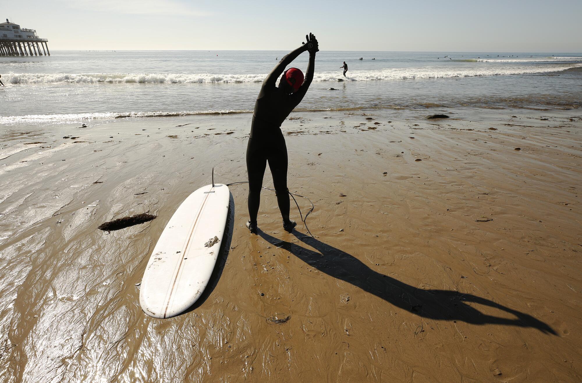 Maria Shen, who began surfing six years ago, stretches before paddling out for a morning session in Malibu.