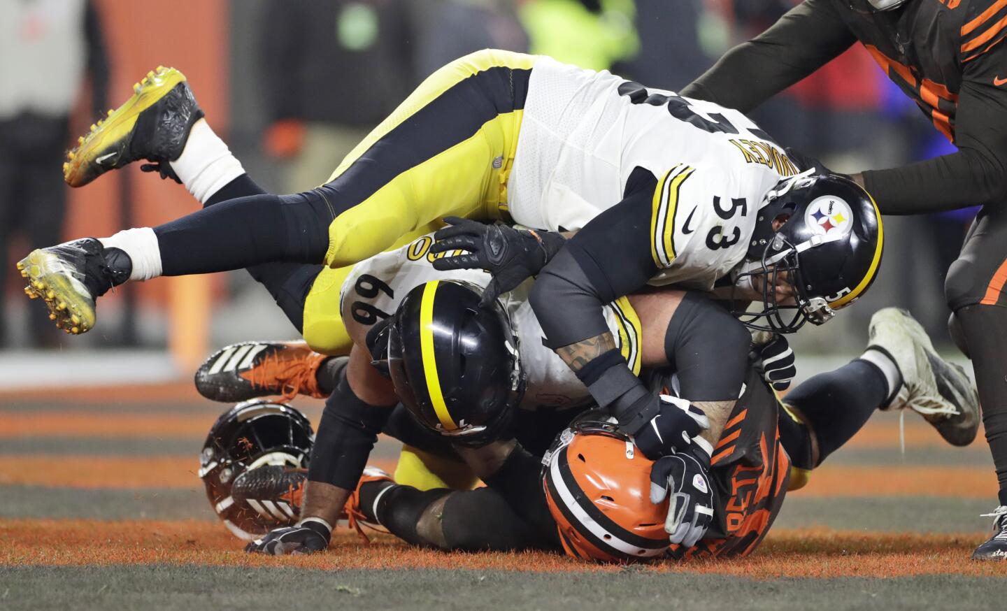 Browns defensive end Myles Garrett, bottom, and, Steelers center Maurkice Pouncey (53) and offensive guard David DeCastro (66) fall to the turf during a brawl on Nov. 14.