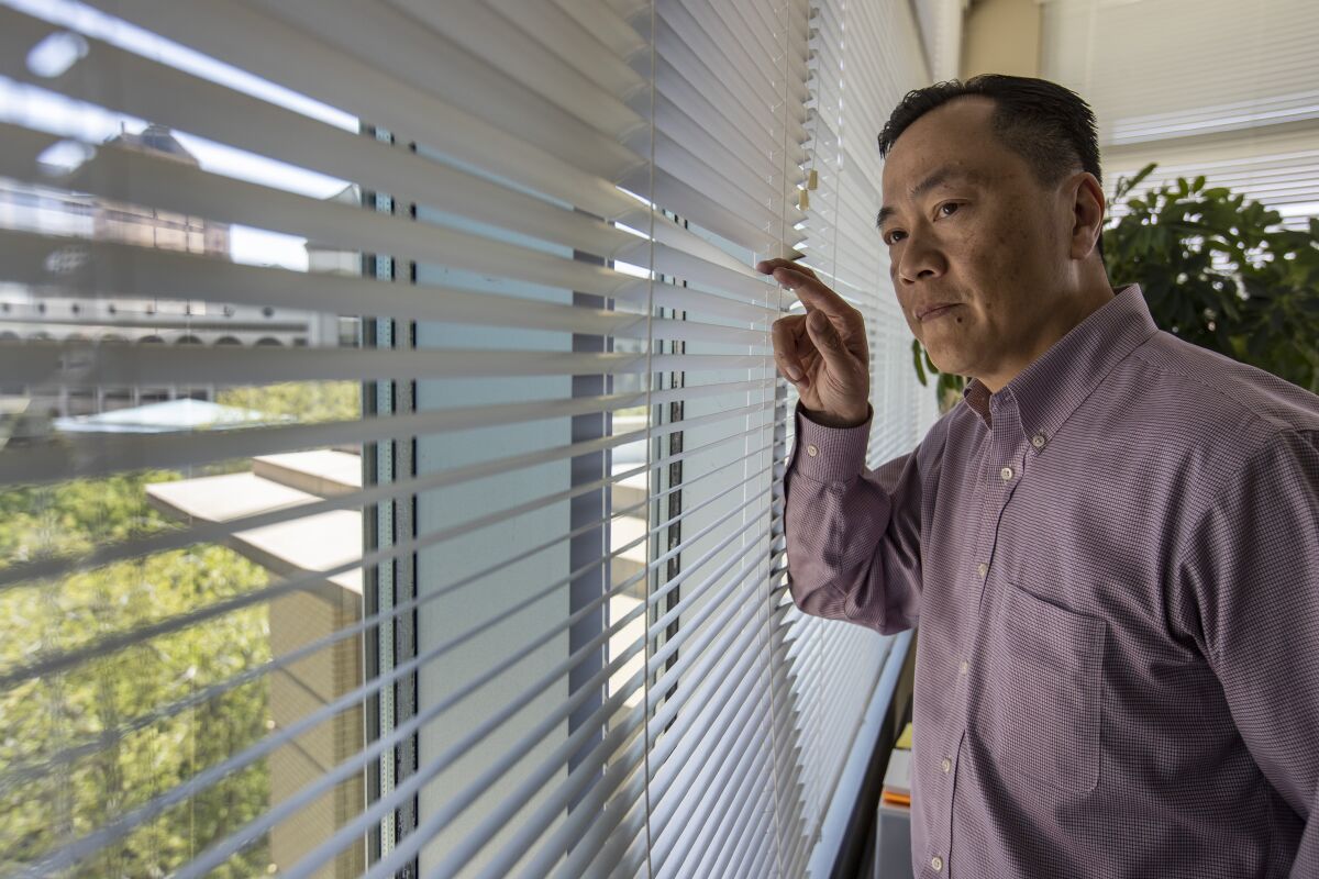Sacramento City Manager Howard Chan looks through the window blinds at his office.