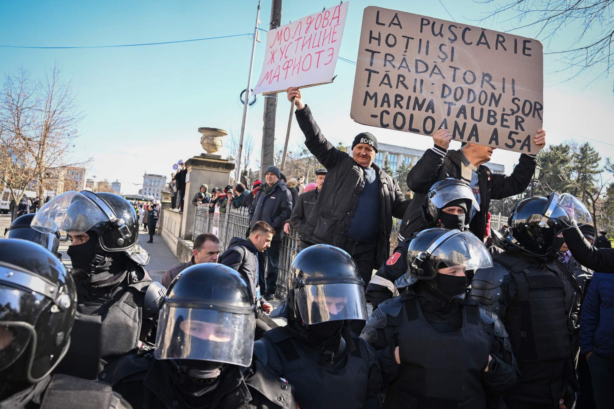 Demonstrators hold signs, one that reads, "Thieves and traitors to jail"