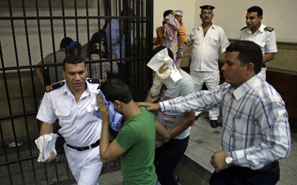 Eight Egyptian men convicted of "inciting debauchery" following their appearance in a video at a party on a Nile boat cover their faces as they leave the defendant's cage in a courtroom in Cairo on Saturday.