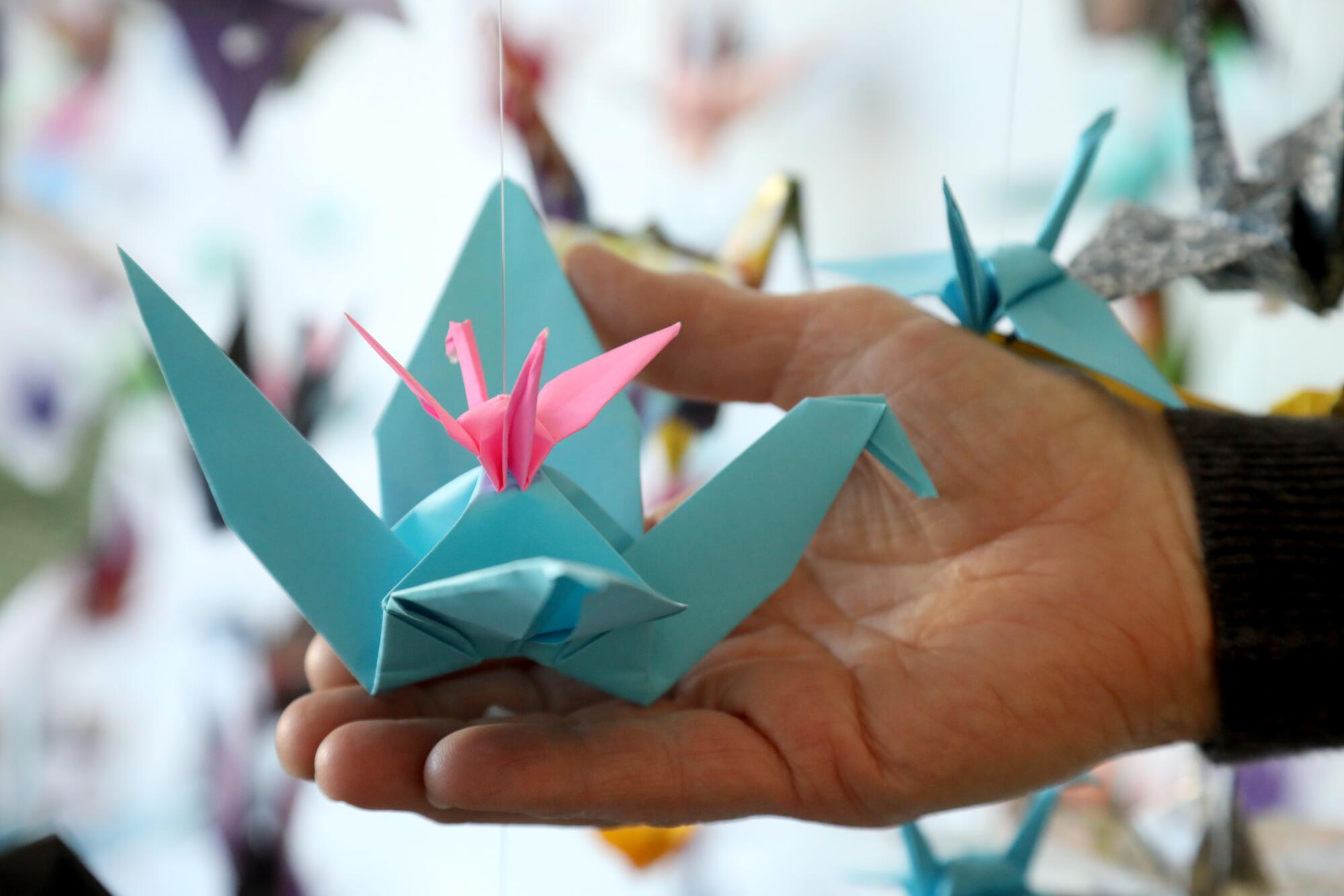 Karla Funderburk holds two colorful paper cranes.