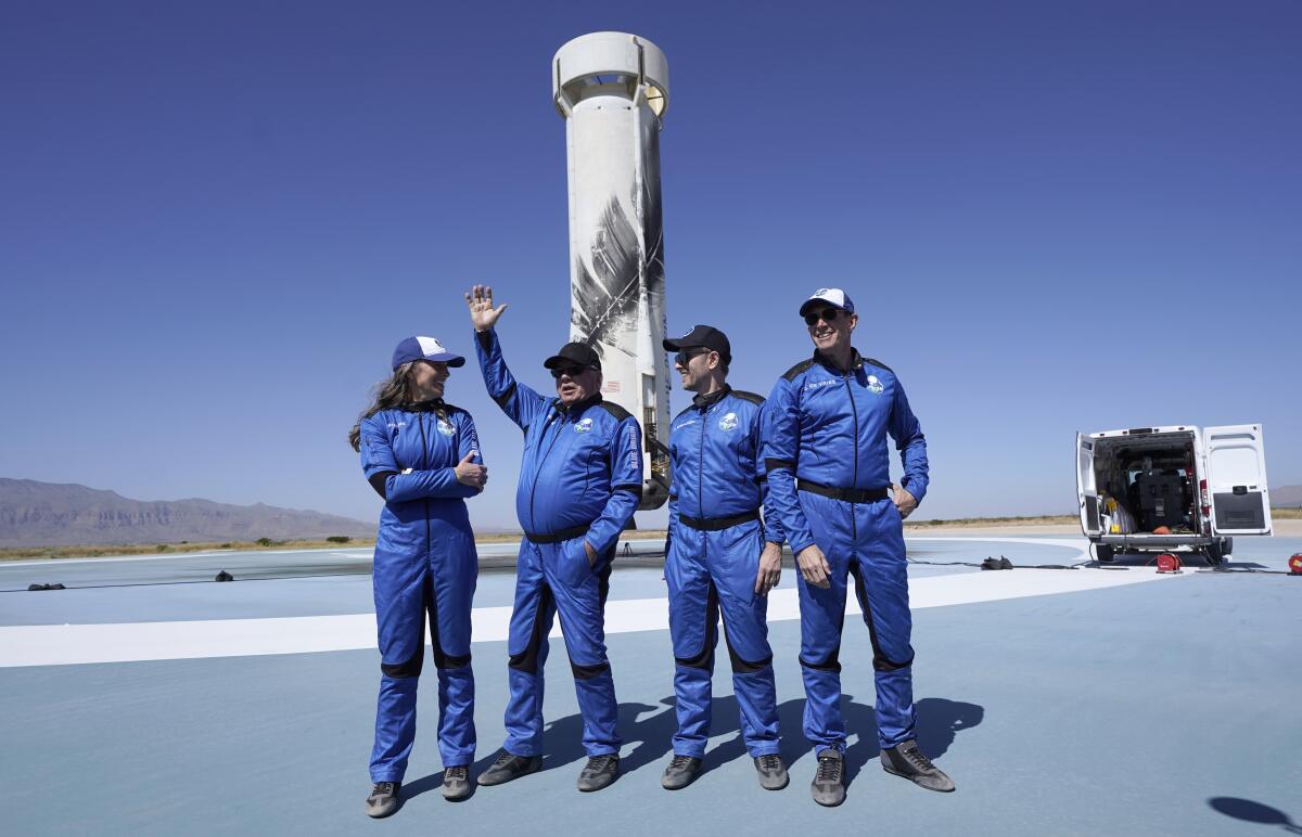 William Shatner, second from left, raises his hand while speaking at the Blue Origin spaceport.