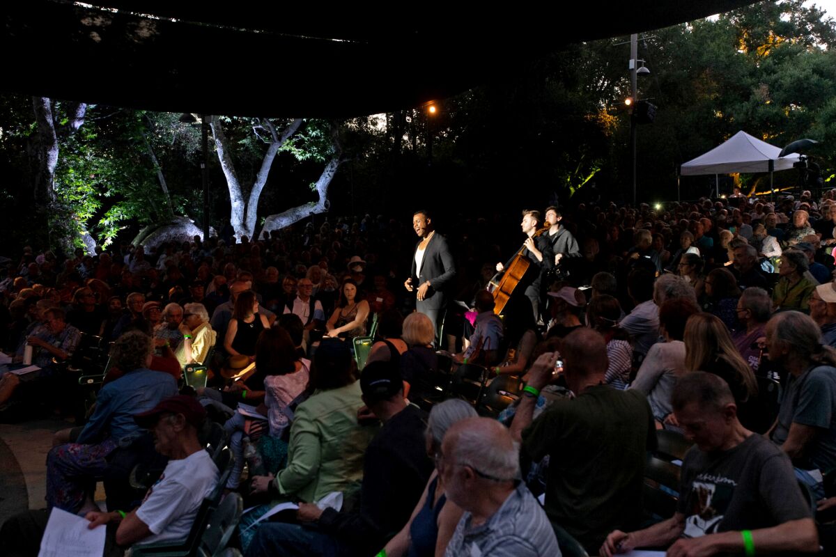 Three men perform amid a crowd in the evening