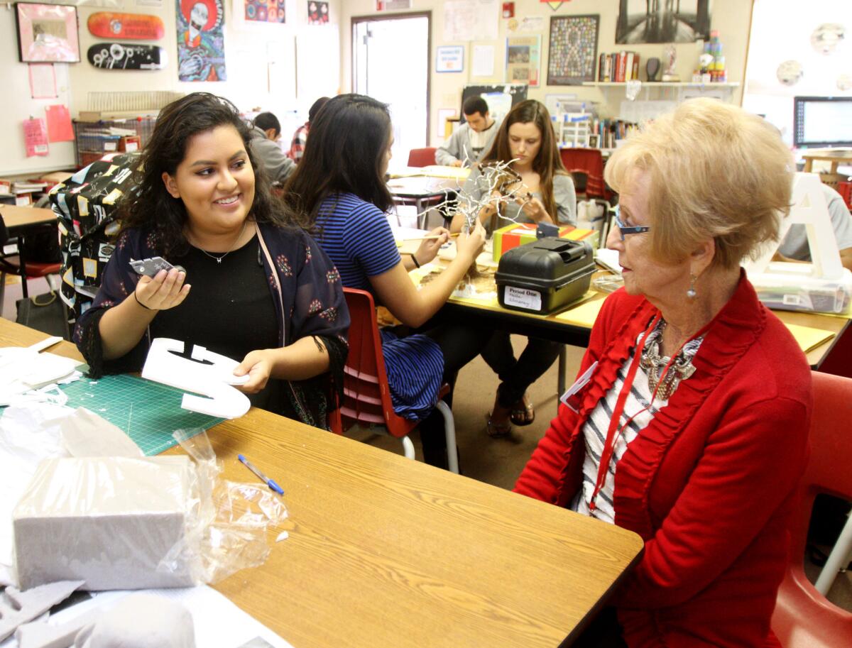 Burroughs High School senior Jackie Gonzalez, left, shows her Senior For a Day companion, Lynn White-Shelby, 81 of Burbank, the symbolic self portrait sculpture she is working on in the advanced art class on Tuesday, March 15, 2016.
