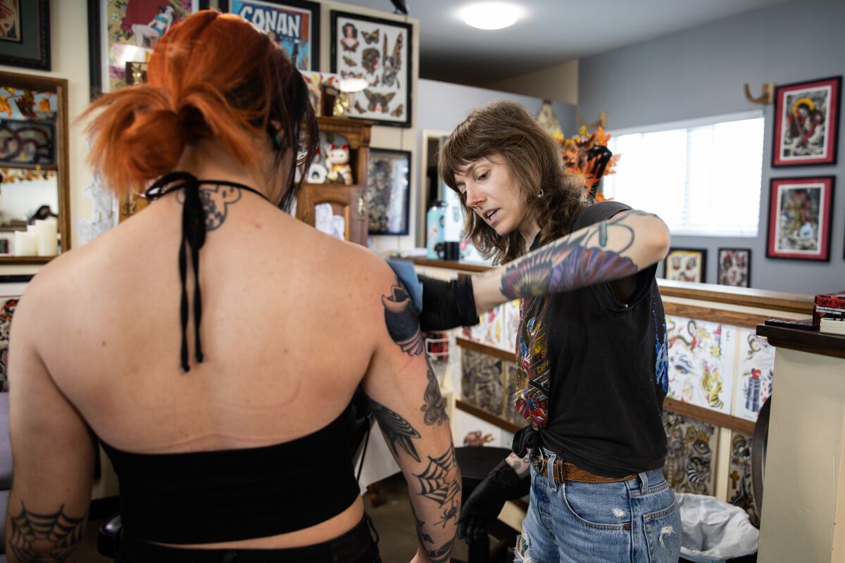 Tattoo artist Lauren Bartram (right) cleans up her client Jasmine Lugo's (left) newest tattoo.