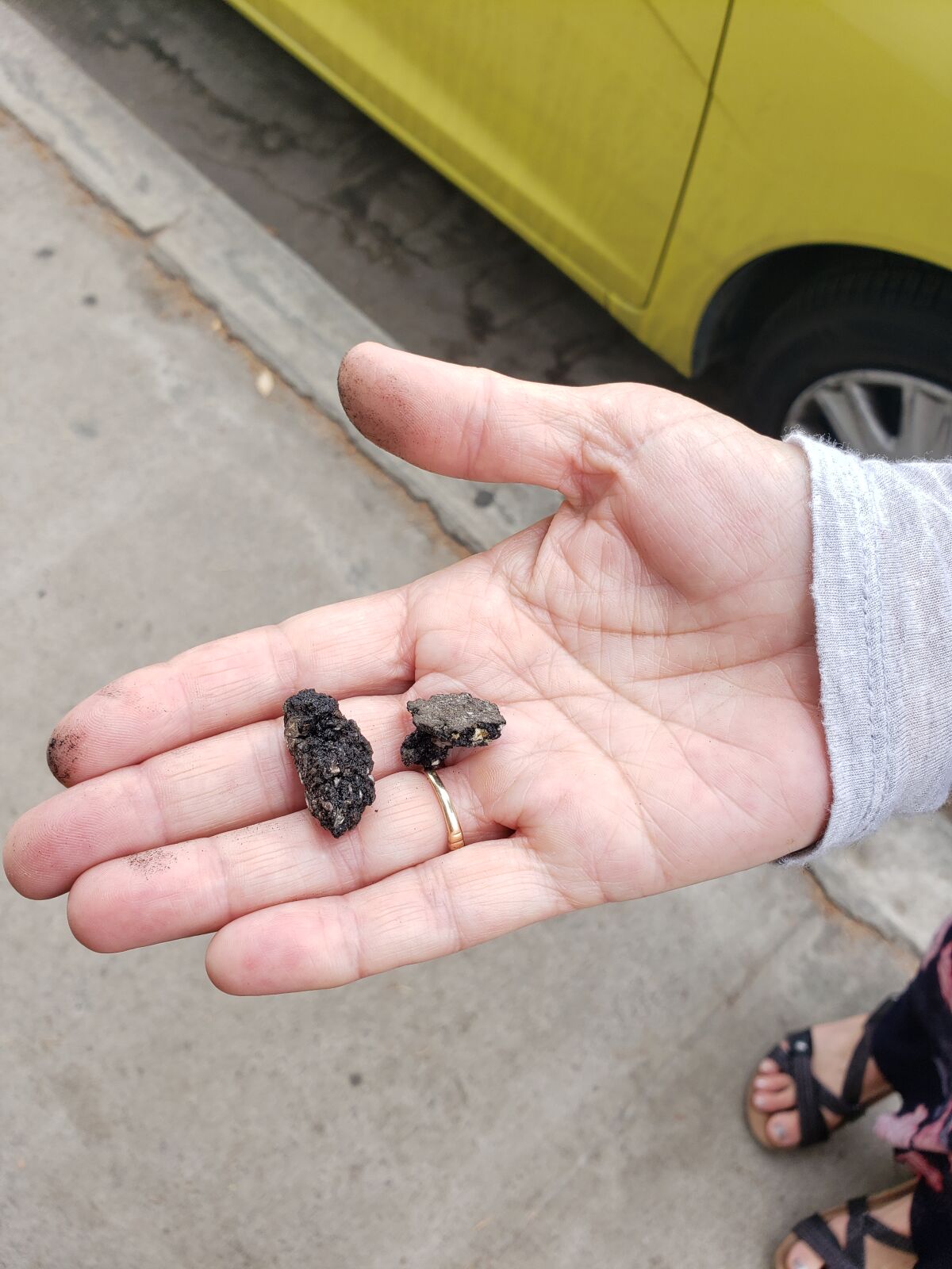 A resident shows the chipping slurry that is present on her street, ahead of a City project to re-slurry the street in the coming months.