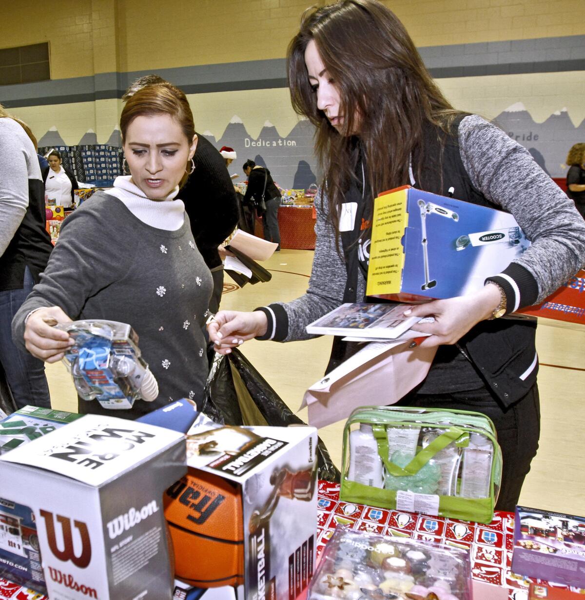 With the help of volunteer Victoria Wells, right, Rosario Ramirez, left, chooses games for her children during the Glendale Salvation Army toy distribution at the Corps gym in Glendale on Thursday, Dec. 19, 2013. About 500 local families were given toys for children up to 12 years old.