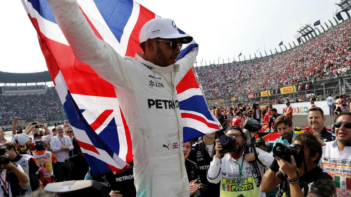 Formula One driver Lewis Hamilton celebrates after his ninth-place finish in the Mexican Grand Prix on Sunday helped him clinch the season championship.