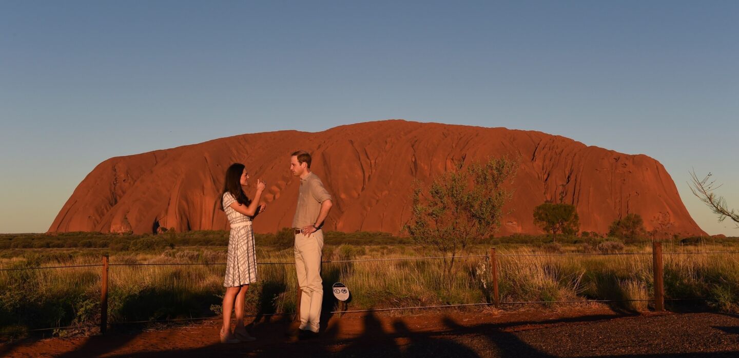 The pair chats before posing for a photo during sunset at Uluru.