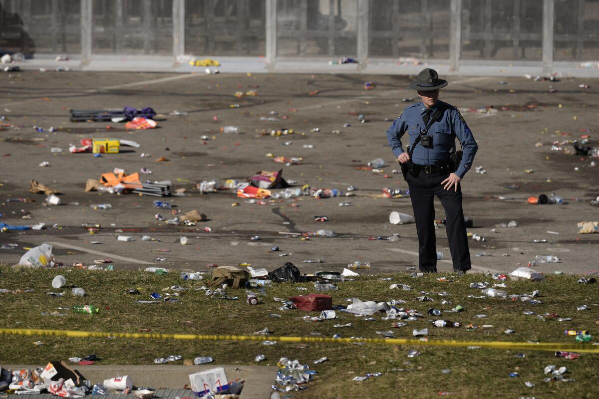 FILE - A law enforcement officer looks around the scene following a shooting at the Kansas City Chiefs NFL football Super Bowl celebration in Kansas City, Mo., Feb. 14, 2024. A third man is now facing murder charges for the Feb. 14 shootings during the Kansas City Chiefs' Super Bowl rally. One woman died and about two dozen other people were hurt in the burst of gunfire. (AP Photo/Charlie Riedel, file)