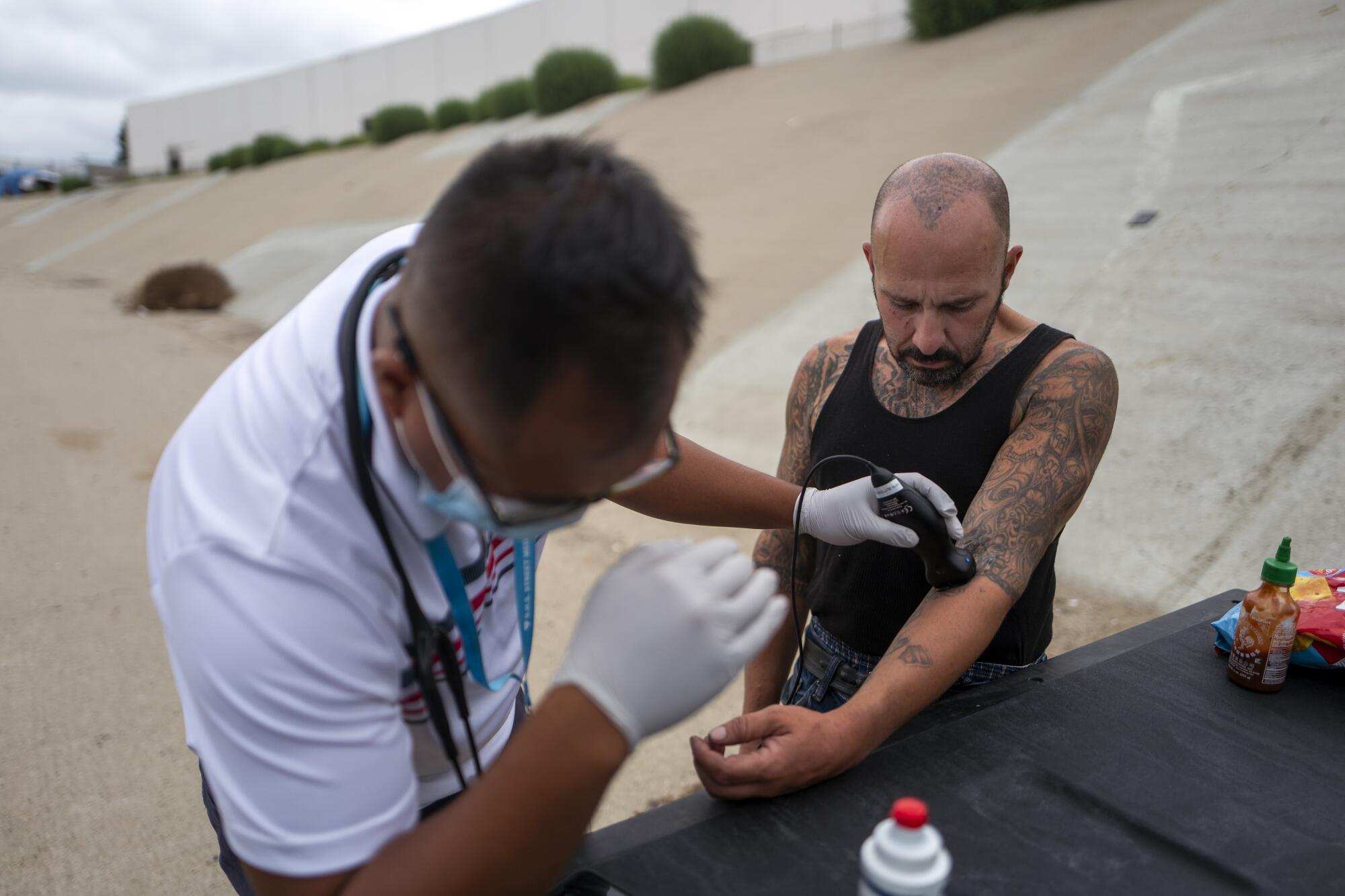 Dr. Absalon Galat, left, uses a portable ultrasound connected to his mobile phone to examine Roy Ramos.