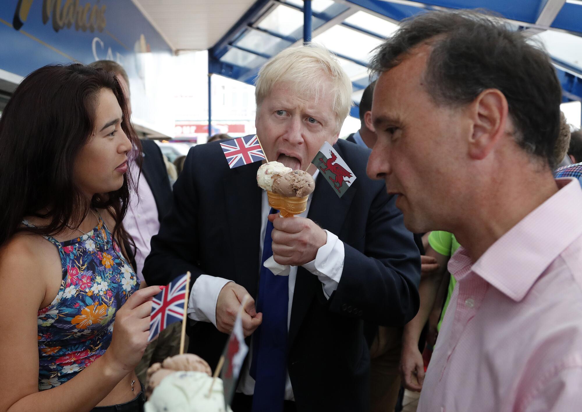 Conservative Party leadership candidate Boris Johnson, center, eats an ice cream cone in Barry Island, Wales, in 2019.