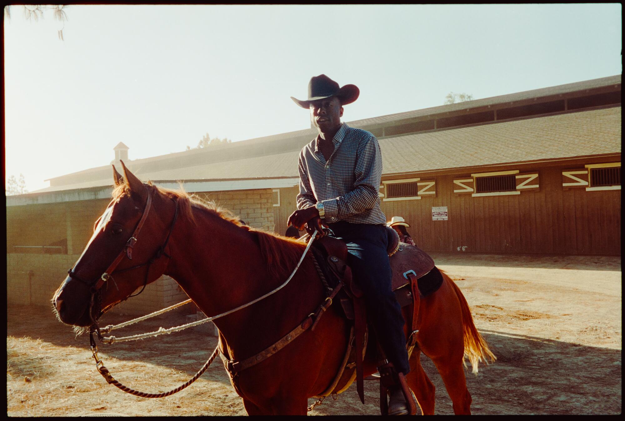 Young Californian cowboy getting his horse out of the stables to prepare for their warm up ahead of the Grand Entry.