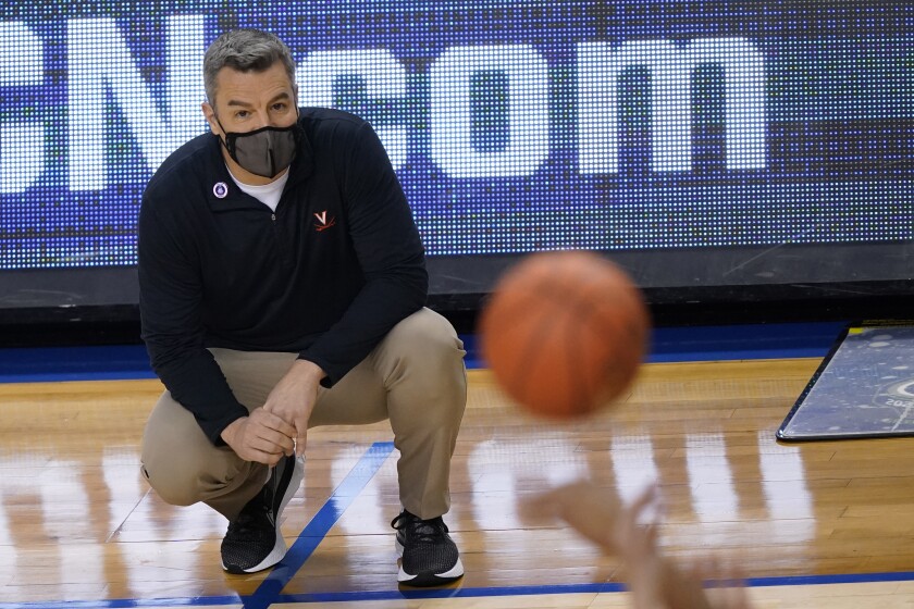 Virginia coach Tony Bennett squats and watches play from the sideline .