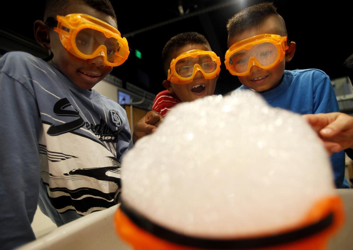 From left, first-graders Jestin Banks, Jacob Campo and Marvin Garcia Jr. complete a science experiment at Alexander Science Center School in Los Angeles. If adopted, new science standards would tackle fewer subjects more deeply and favor hands-on experiments over rote memorization of facts.