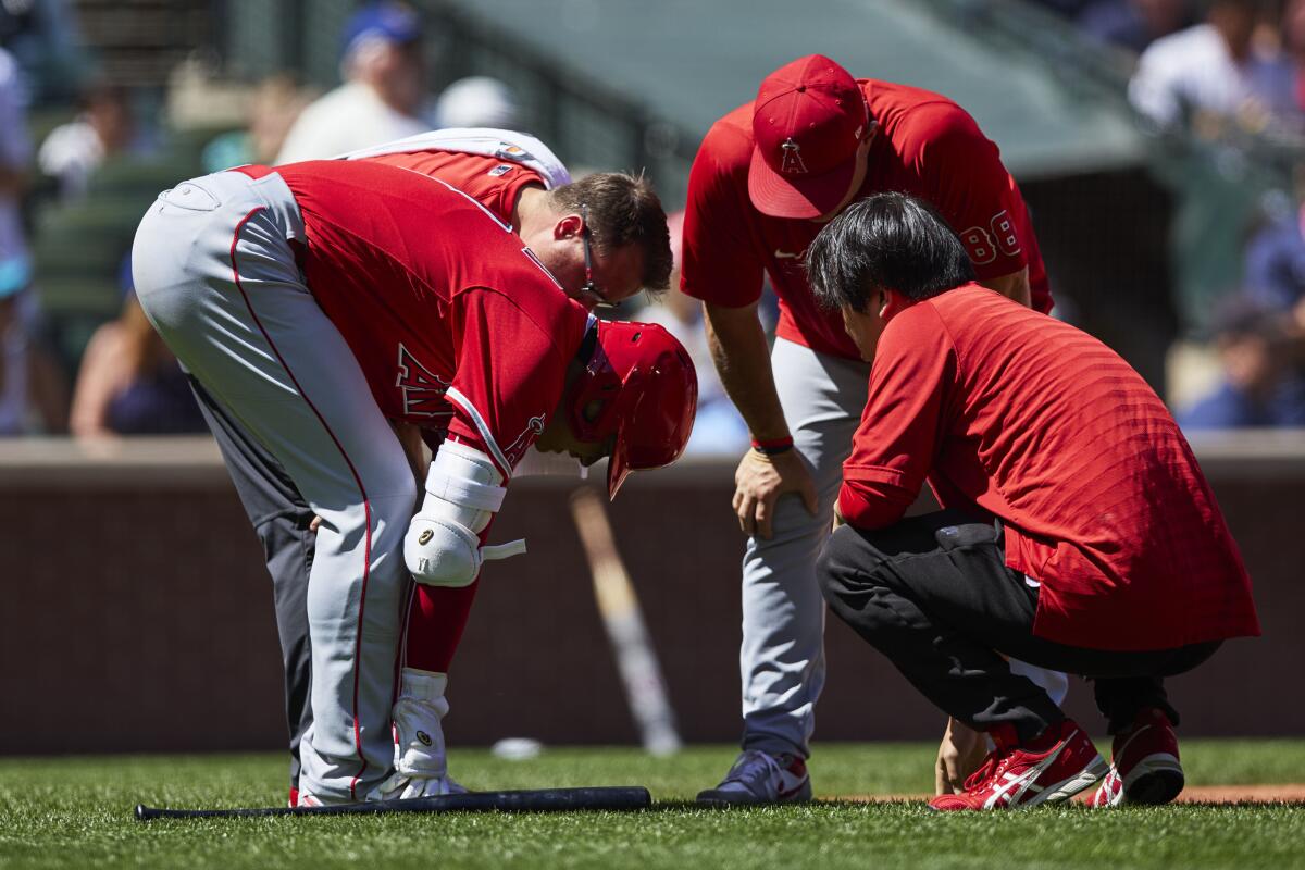 Angels star Shohei Ohtani speaks to a team trainer before batting against the Seattle Mariners.