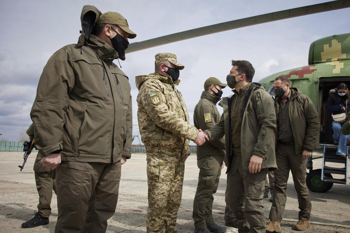 Ukrainian President Volodymyr Zelenskiy shakes hands a soldier as he visits the war-hit Donetsk region, eastern Ukraine, Thursday, April 8, 2021. Ukraine is at the center of a major geopolitical battle in the eastern part of the country with Moscow backed separatists. (Ukrainian Presidential Press Office via AP)